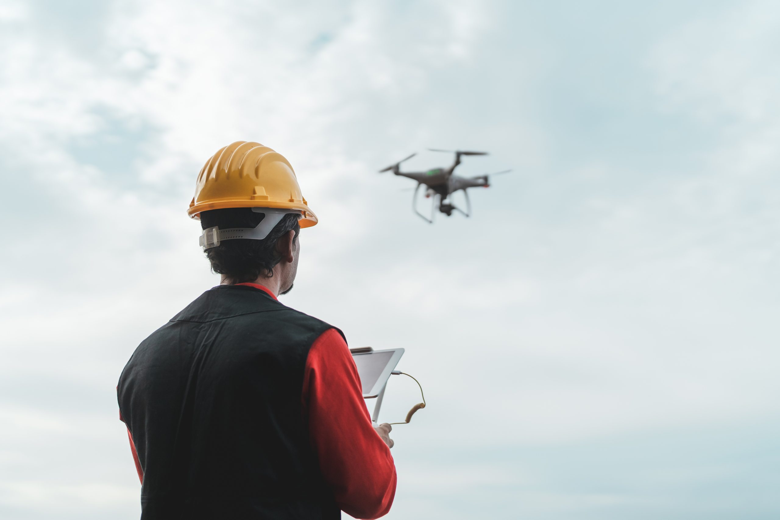 Nadzory budowlane - mężczyzna obsługujący drona monitorującego postęp prac budowlanych