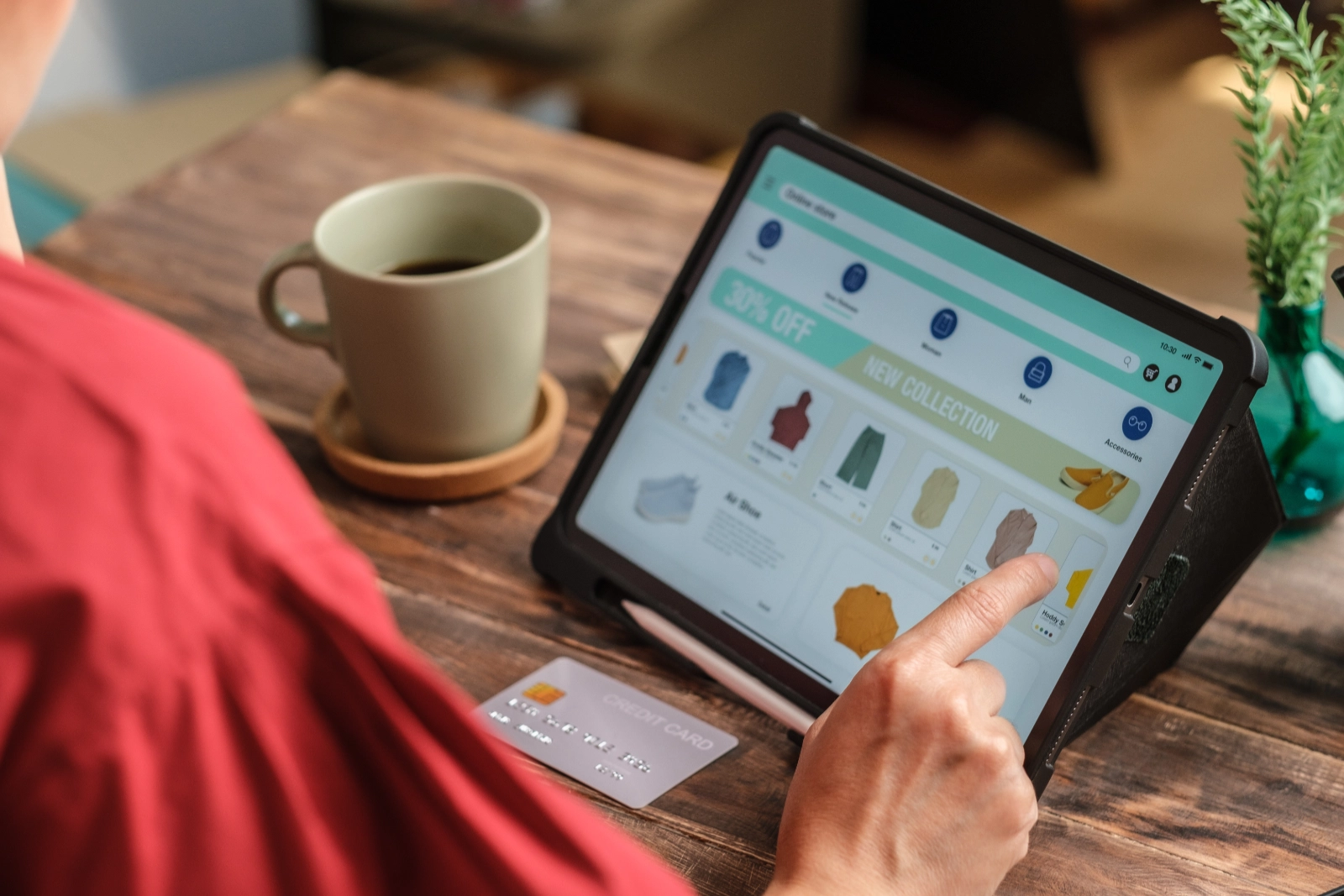 Osoba przeglądająca ofertę sklepu internetowego na tablecie z kartą kredytową